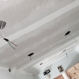 OdRemontuj - Sufit podwieszany w trakcie montażu z widocznymi otworami na oświetlenie i wystającymi przewodami elektrycznymi, szpachlowane łączenia płyt gipsowo-kartonowych.