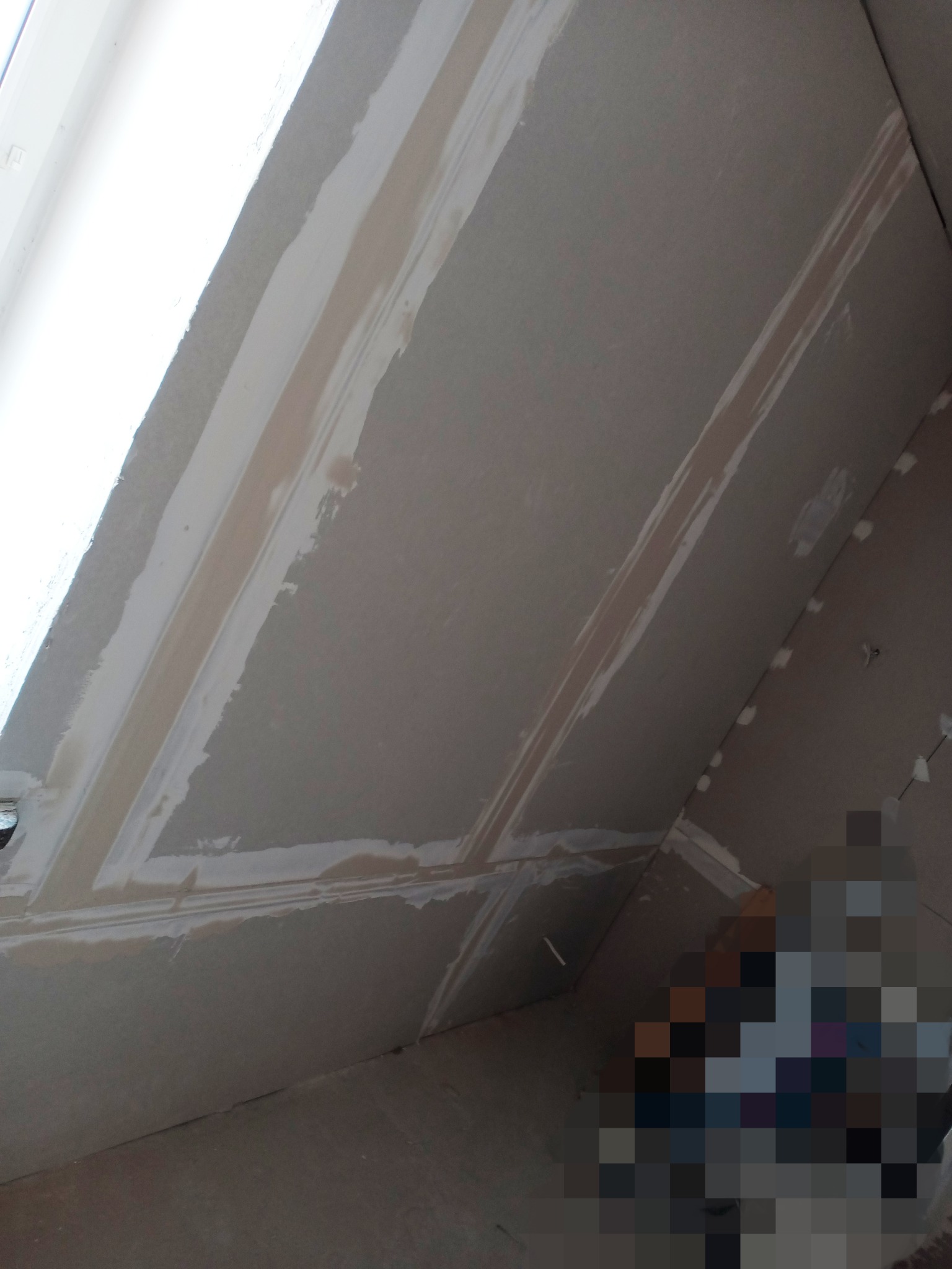 Sufit poddasza z płyt gipsowo-kartonowych w trakcie szpachlowania łączeń, widoczne ślady po taśmie wzmacniającej i świeżo nałożonej masie szpachlowej.