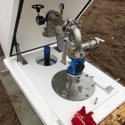 Wierttrans - Gotowa instalacja studni w Kwidzynie, widoczne metalowe rury, zawory, manometr oraz czarna rura wystająca z otworu, całość zamknięta w białej skrzynce.