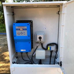 Wierttrans - Otwarta biała skrzynka sterownicza Speedbox Coelbo z widocznymi elementami elektrycznymi i okablowaniem, zamontowana na zewnątrz, w tle drzewa.