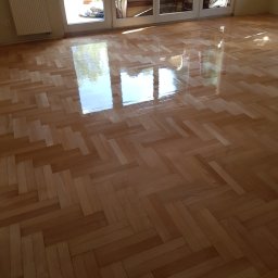 E&P EURO-HOME - Świeżo wycyklinowany, lakierowany parkiet ułożony w jodełkę, odbijający światło z okna tarasowego.