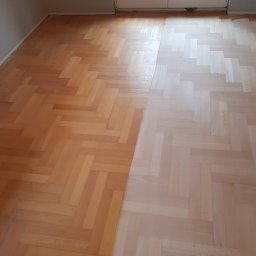 E&P EURO-HOME - Fragment podłogi z parkietu ułożonego w jodełkę, po lewej stronie widoczna część podłogi po renowacji, po prawej przed renowacją, w tle widoczne drzwi balkonowe i fragment ściany.