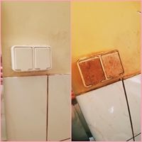 Porównanie stanu włącznika światła przed i po czyszczeniu. Po lewej stronie włącznik jest czysty, biały, a po prawej brudny, pokryty brązowym nalotem. Widoczne płytki ceramiczne w tle.