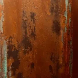 Tekstura ściany z wyraźnymi śladami rdzy i zielonkawymi zaciekami, ukazująca proces korozji i zmiany koloru.