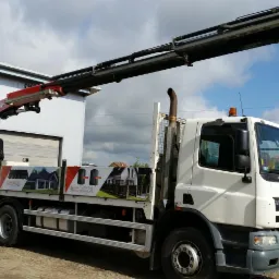 Ciężarówka z dźwigiem hydraulicznym, na boku reklama metalowych dachów i elewacji budynków.