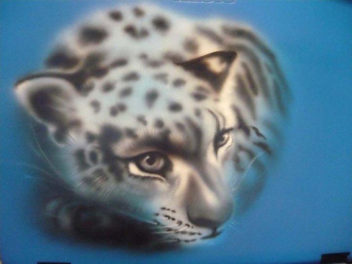 Airbrush przedstawiający portret pantery śnieżnej na błękitnym tle.