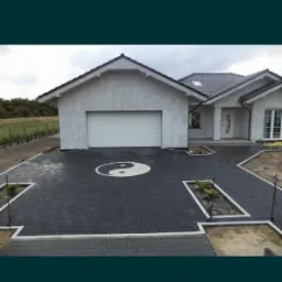 Ułożona kostka betonowa w kolorze grafitowym przed domem z motywem Yin Yang z jasnej kostki.