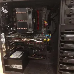 Wnętrze obudowy komputera stacjonarnego z widoczną płytą główną, kartą graficzną MSI, chłodzeniem procesora i zasilaczem Corsair VS550.