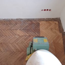 Posadzkarstwo Piotr Dąbrowa - Cyklinowanie parkietu ułożonego w jodełkę; widoczna maszyna do cyklinowania i fragment podłogi przed i po cyklinowaniu.