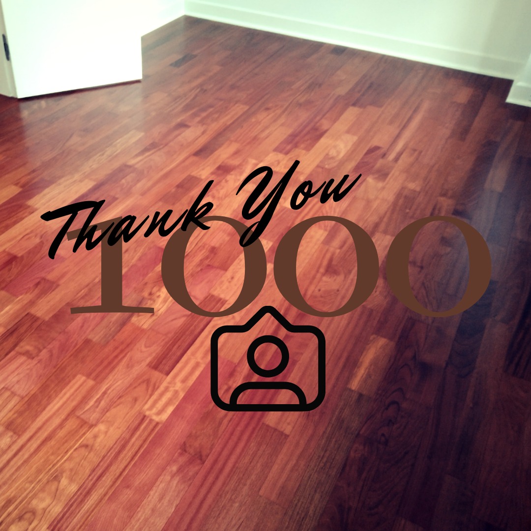 Wykończona podłoga z desek o ciepłym, czerwono-brązowym odcieniu, z nałożoną grafiką 'Thank You 1000', symbolizującą podziękowanie za tysiąc obserwujących lub klientów.