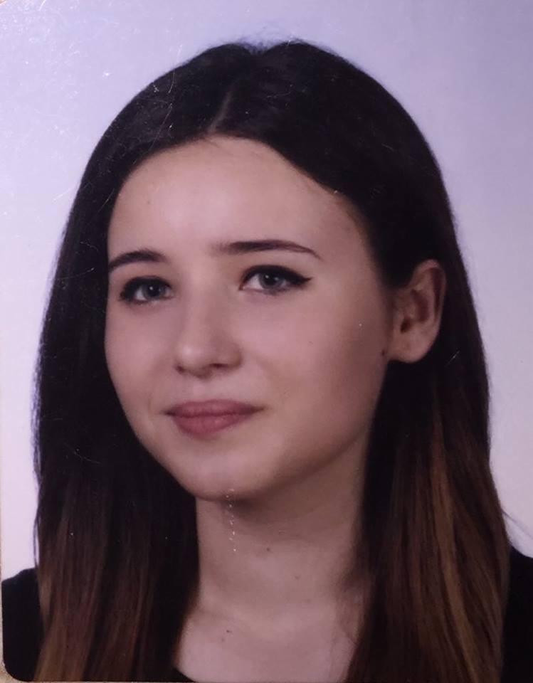 Portret młodej kobiety z ciemnymi włosami z brązowymi refleksami, delikatny makijaż, skierowana wprost, na jasnym tle.