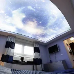 Sypialnia z podświetlanym sufitem imitującym rozgwieżdżone niebo, widok z łóżka, niebieskie ściany, okno z zasłonami w biało-granatowe pasy, telewizor na ścianie.