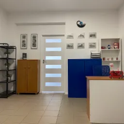 Jasne wnętrze szkoły językowej z recepcją, regałem z dekoracjami nawiązującymi do Wielkiej Brytanii i grafikami przedstawiającymi Londyn.