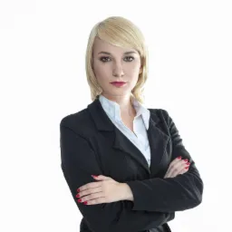 Portret kobiety w czarnym żakiecie i białej koszuli, skrzyżowane ręce, czerwone paznokcie, jasne włosy, na jasnym tle. Profesjonalny wizerunek.
