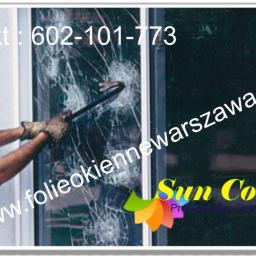 PPUH Sekret-foll - Mężczyzna w okularach i rękawicach ochronnych wyważa okno przy użyciu łomu. Szyba popękana, widoczne logo firmy i dane kontaktowe na zdjęciu.