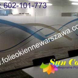 PPUH Sekret-foll - Szklana ściana biurowa z dekoracyjną folią okienną w kolorze niebieskim i beżowym, z numerem telefonu kontaktowego i adresem strony internetowej, widoczne krzesła i biurko w tle.