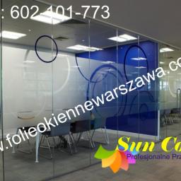 PPUH Sekret-foll - Szklana ściana działowa w biurze z naniesionymi dekoracyjnymi okręgami w kolorze białym i niebieskim, widoczny numer kontaktowy i adres strony internetowej.