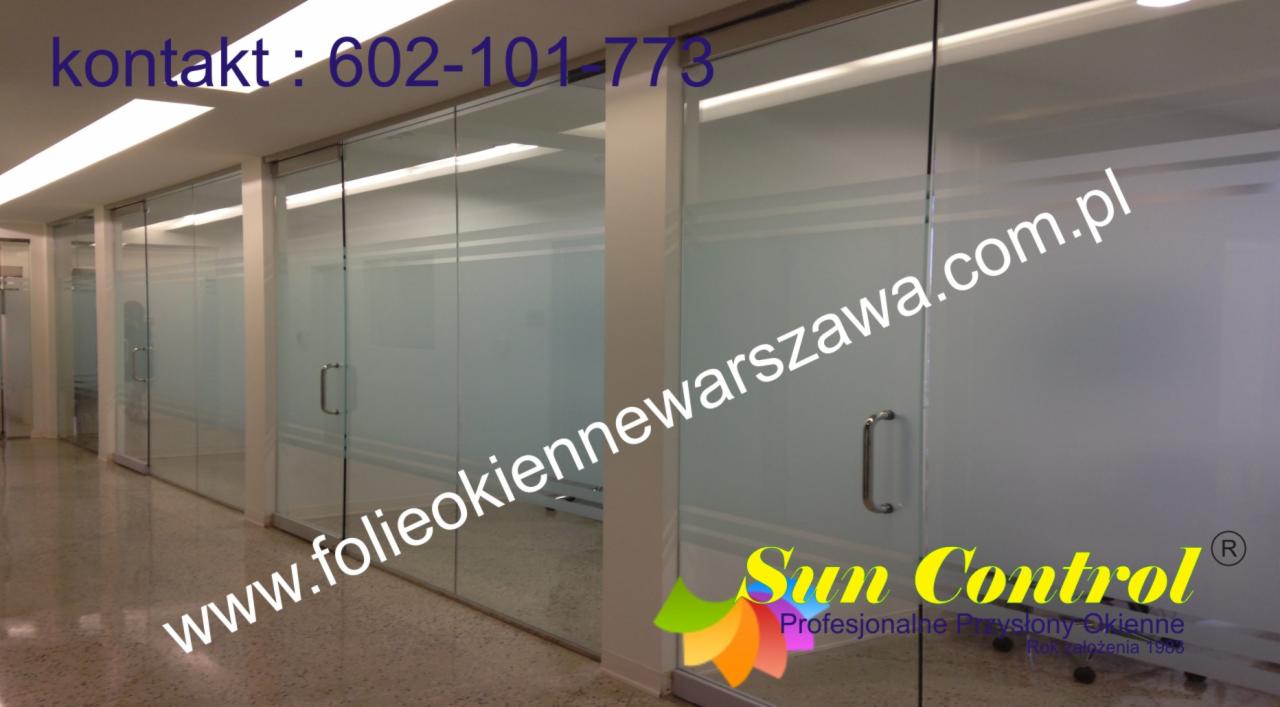 Przeszklone biuro z folią okienną, widoczne logo Sun Control i adres strony internetowej na szybie.