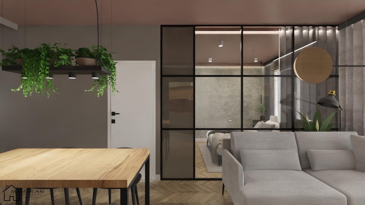 Wizualizacja salonu z drewnianym stołem, sofą i przeszkloną ścianą oddzielającą sypialnię, nad stołem wisząca platforma z roślinami i oświetleniem punktowym.