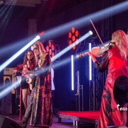 Elite Music Julian Dziewulski - Zespół muzyczny na scenie z oświetleniem eventowym. Wokalistki grają na skrzypcach, perkusistka w tle. Koncert w Radisson Blu Sopot, realizacja Rolmar.