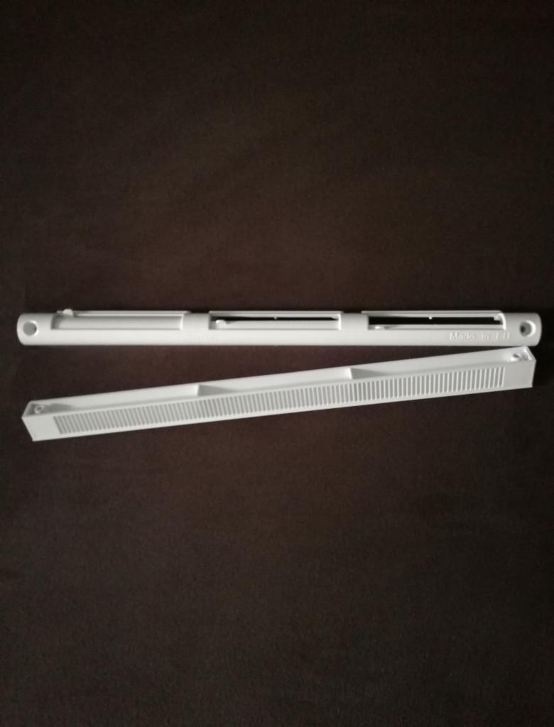 Dwa białe, plastikowe elementy wentylacyjne na brązowym tle, jeden z napisem 'Made in EU'.