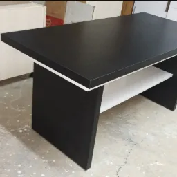 Czarny blat na wspornikach z półką, wykonany na wymiar, z białym obramowaniem, na tle jasnych szafek.