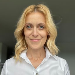 Gabinet Zmian Psychoterapia Urszula Sokalska-Goleń - Portret uśmiechniętej blondynki o niebieskich oczach, w białej koszuli, na rozmytym tle. Profesjonalny wizerunek.