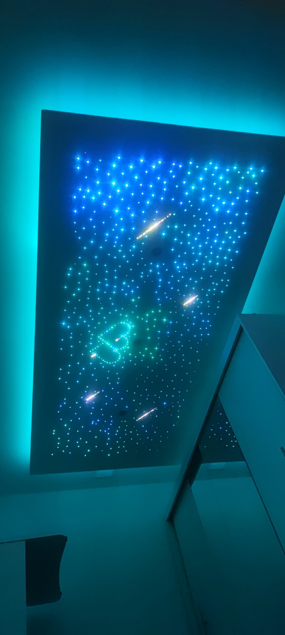 Podwieszany sufit z efektem rozgwieżdżonego nieba, z niebieską poświatą na krawędziach i motywem zielonego serca pośrodku.