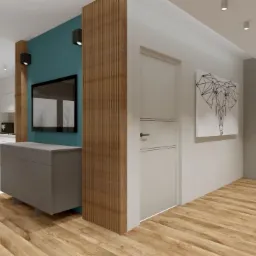 Wnętrze mieszkania z drewnianą podłogą, ścianą w kolorze turkusowym, szarą komodą pod telewizorem i drewnianą ścianką działową z pionowych listew. W tle widoczna kuchnia z białymi meblami...