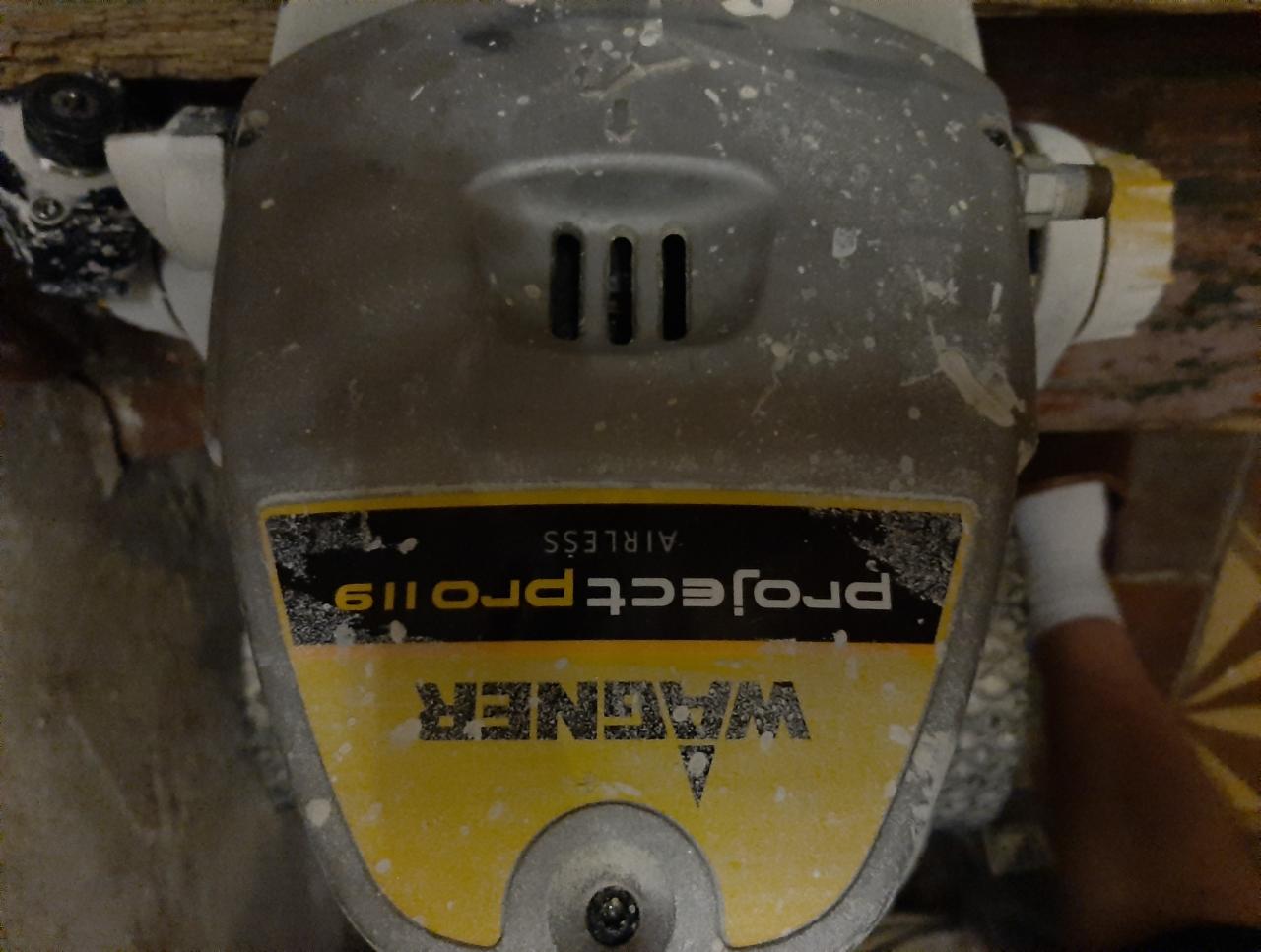 Używany agregat malarski Wagner Project Pro 119 z widocznymi śladami farby, ustawiony na podłodze w trakcie remontu mieszkania.