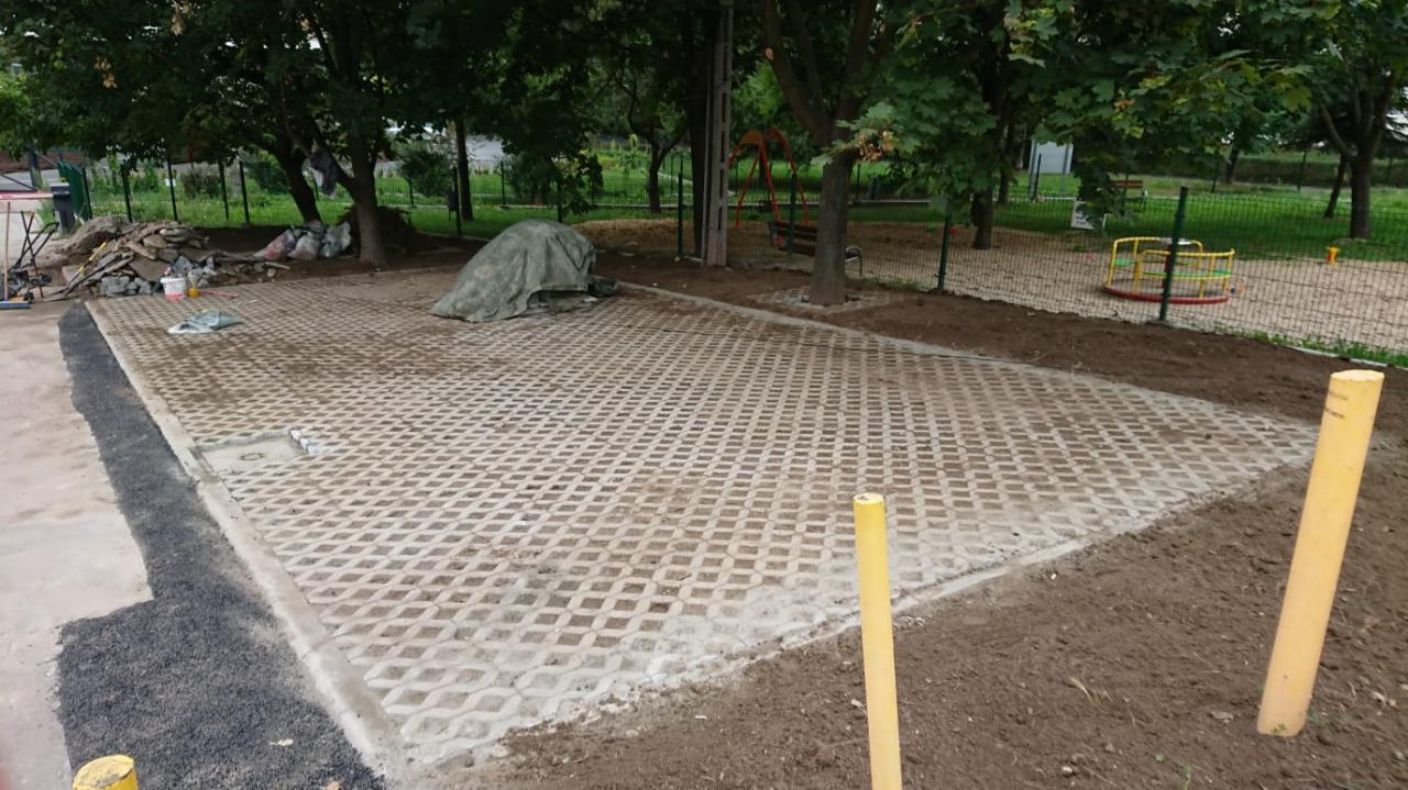 Ułożona ażurowa kostka brukowa na placu zabaw, widoczne przygotowane materiały, plac w trakcie prac wykończeniowych.