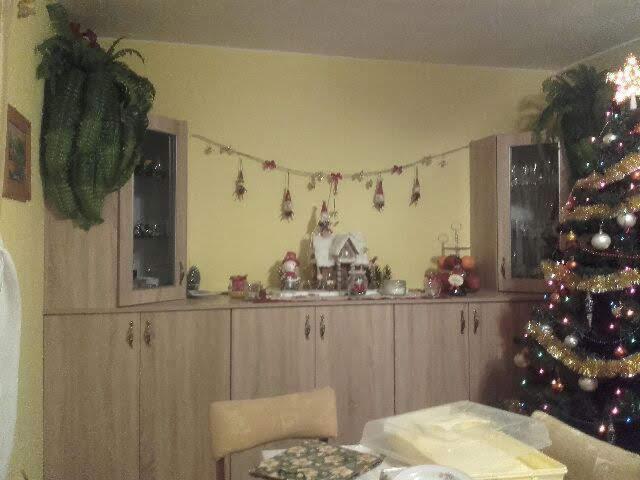 Świątecznie udekorowany pokój z meblami na wymiar w odcieniach drewna, z wiszącą girlandą, choinką i dekoracjami.