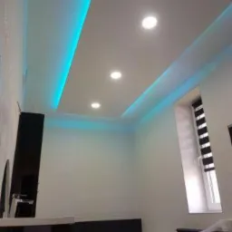 Nowoczesna łazienka z podwieszonym sufitem, oświetleniem LED w kolorze turkusowym i punktowymi lampami, widok z dołu.