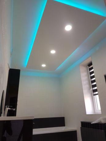 Nowoczesna łazienka z podwieszonym sufitem, oświetleniem LED w kolorze turkusowym i punktowymi lampami, widok z dołu.