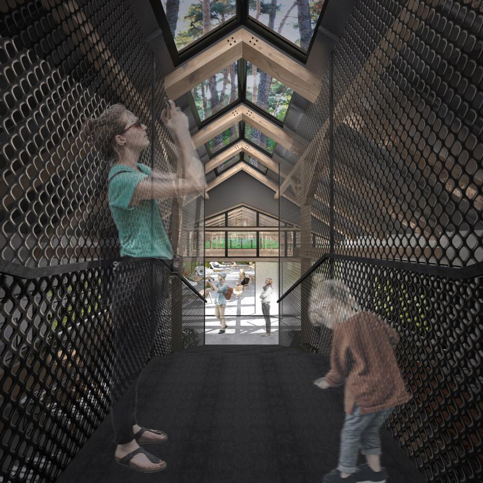 Wnętrze budynku z przeszklonym dachem i ażurowymi ścianami, kobieta robi zdjęcie telefonem, dziecko schodzi po schodach, widok na zewnątrz na grupę ludzi i zieleń.