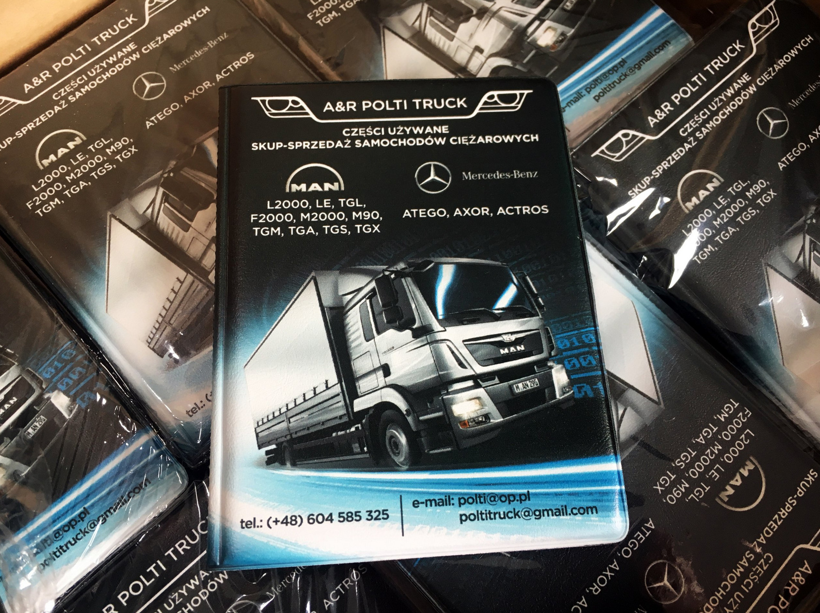 Stos ulotek reklamowych firmy A&R Polti Truck z grafiką ciężarówki MAN, logo MAN i Mercedes-Benz oraz informacjami kontaktowymi, ułożonych ciasno obok siebie.