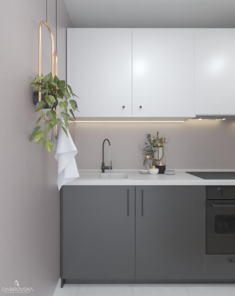 Nowoczesna kuchnia z szarymi szafkami dolnymi i białymi górnymi, czarna bateria i wisząca złota konstrukcja z rośliną doniczkową oraz białą ściereczką.