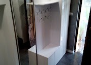 Biała szafa wnękowa z lustrem i wieszakami, widok z boku, oświetlenie dzienne, minimalistyczny design, szara ściana w tle.