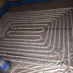 KAMENERGIA - Układ rur ogrzewania podłogowego, zamocowanych do siatki zbrojeniowej, zalewanych betonem, widok z góry w trakcie instalacji.