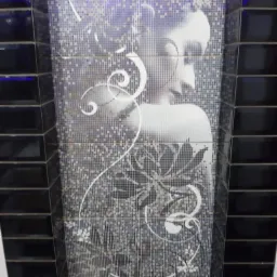 Mozaika w łazience z motywem kobiety i ornamentami roślinnymi, obramowana czarnymi, błyszczącymi płytkami. Dekoracyjne wykończenie ściany.