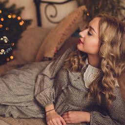 MWFotografia - Kobieta z blond lokami, w sukience z kołnierzykiem, leży na łóżku na tle choinki z lampkami, profil, spokojny wyraz twarzy.