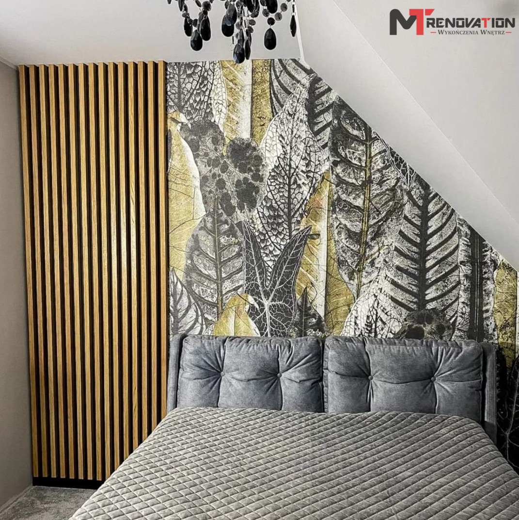 Nowoczesna sypialnia na poddaszu z drewnianą ścianką działową, tapetą w liście i szarą tapicerowaną ramą łóżka.