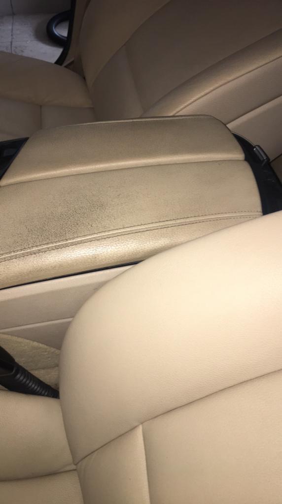 Beżowa skórzana tapicerka samochodowa z widocznymi śladami użytkowania i zabrudzeniami na podłokietniku.