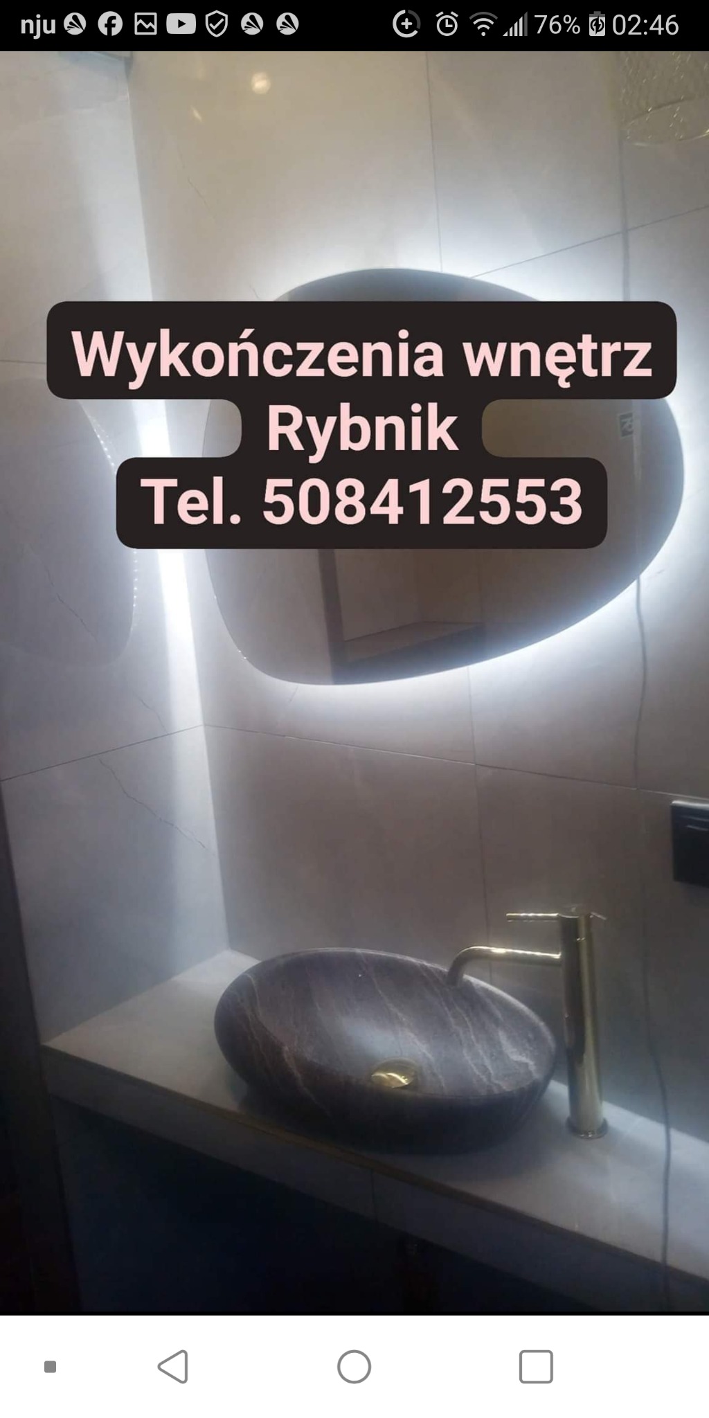 Wykończona łazienka z umywalką z ciemnego marmuru, złotą baterią i podświetlanym lustrem, widoczne płytki na ścianie.