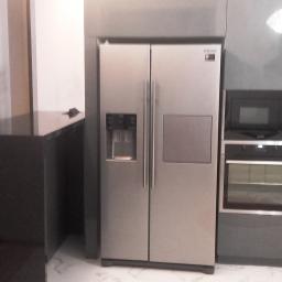 PPUH NIXSTYL - Szara zabudowa kuchenna z dużą lodówką side-by-side, piekarnikiem i mikrofalówką; w tle widoczna choinka.