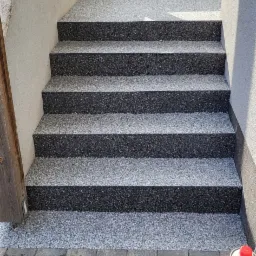 Schody wejściowe wykończone żywicą epoksydową z widocznymi narzędziami i materiałami do aplikacji.