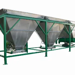 Metalowa konstrukcja z trzema zbiornikami lejowymi, wsparta na zielonym, stalowym stelażu, z widocznymi elementami przenośników taśmowych i silników.