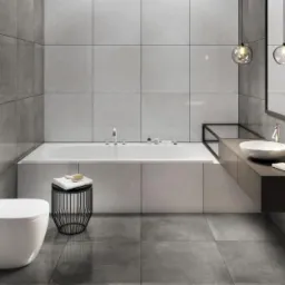 Nowoczesna łazienka z szarymi płytkami, wiszącą toaletą, wanną obudowaną panelami, umywalką nablatową i okrągłymi lampami wiszącymi.