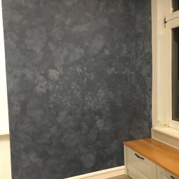 LAPIS HOME SP. Z O. O. - Ściana z dekoracyjnym malowaniem w odcieniach szarości, widoczna obok białej ramy okiennej i zabudowanej szafki z drewnianym blatem.