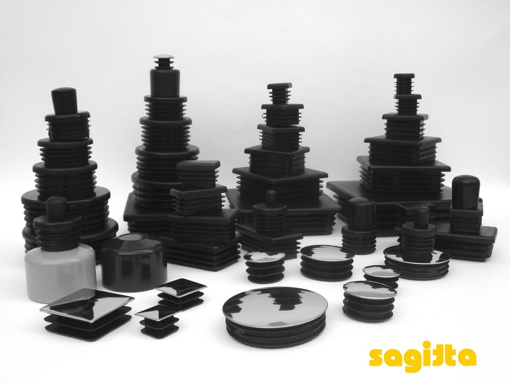 Zestaw różnorodnych czarnych zaślepek i daszków z tworzywa sztucznego o różnych kształtach i rozmiarach, ułożonych na białym tle, widoczne logo firmy Sagista w prawym dolnym rogu.